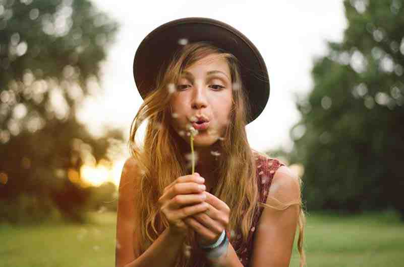 Image of a woman outside blowing on a dandilion